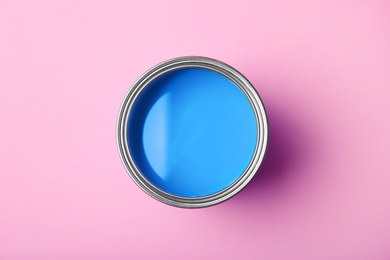 Photo of Can with blue paint on pink background, top view