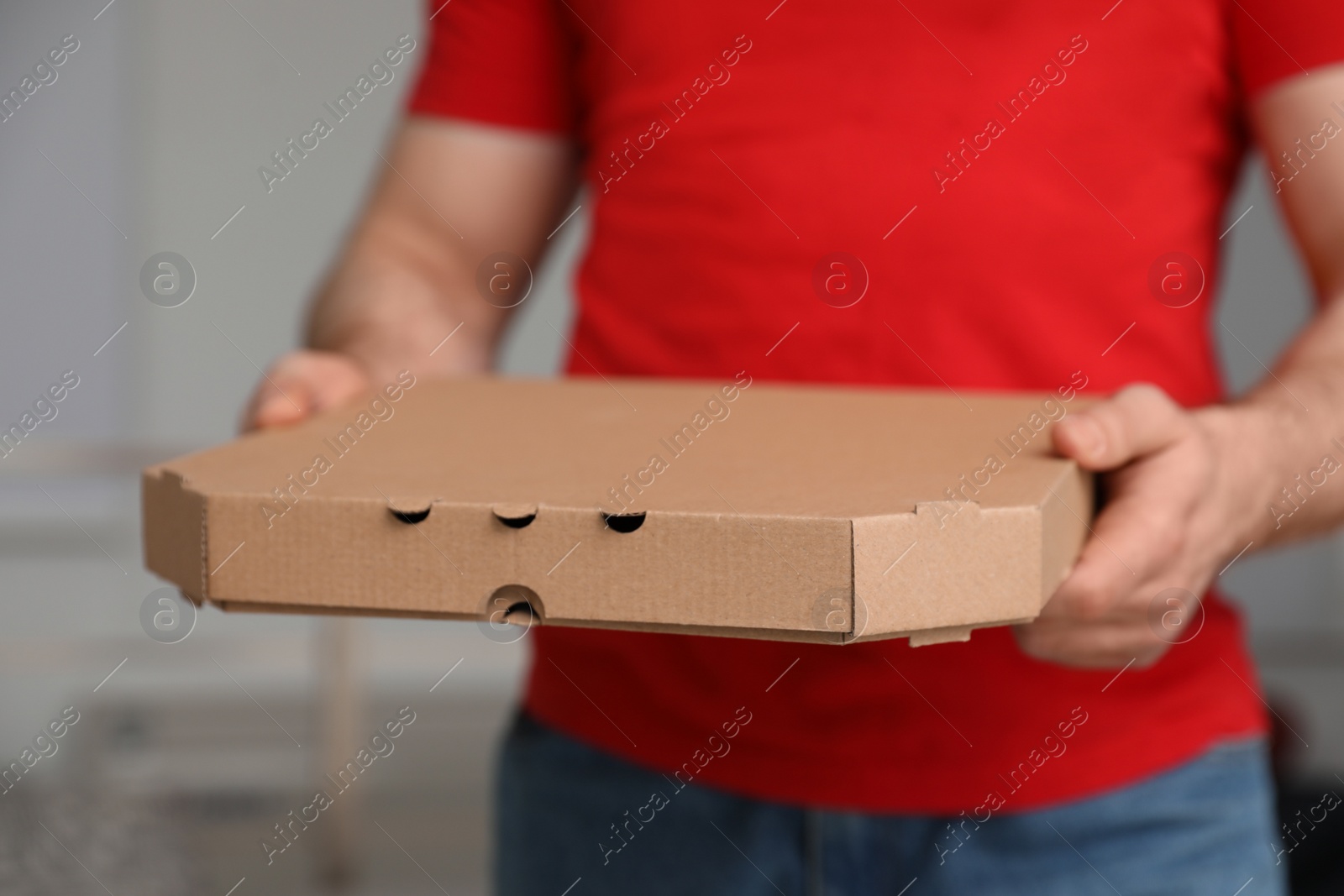 Photo of Courier with pizza box on blurred background, closeup