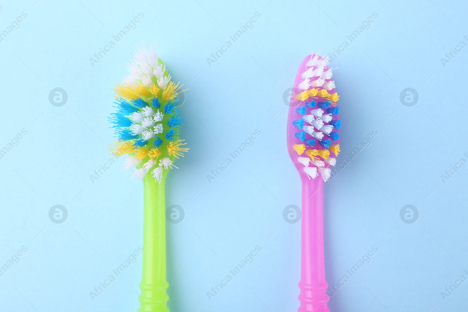 Photo of Colorful plastic toothbrushes on light blue background, flat lay