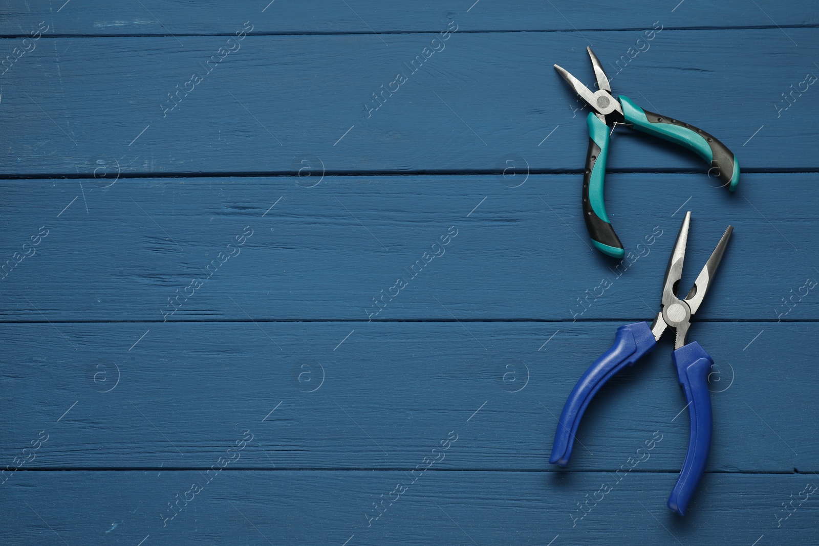 Photo of Pliers on blue wooden table, flat lay. Space for text