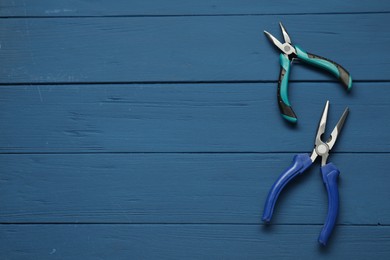 Pliers on blue wooden table, flat lay. Space for text