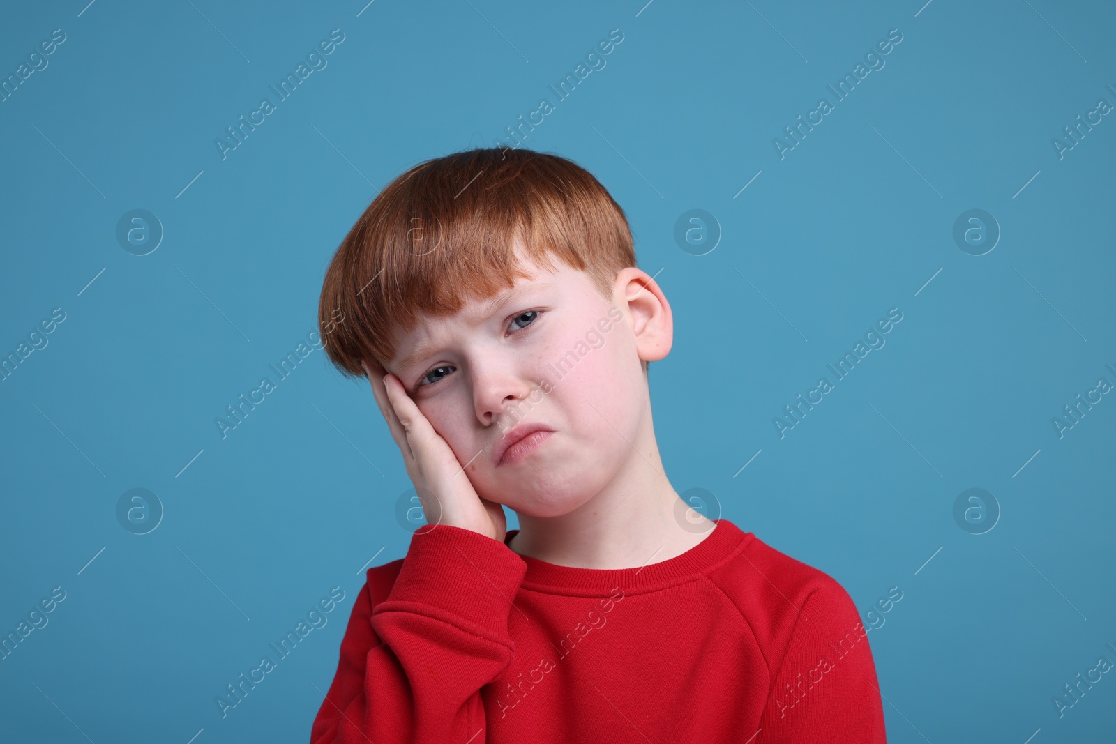 Photo of Portrait of sad little boy on light blue background