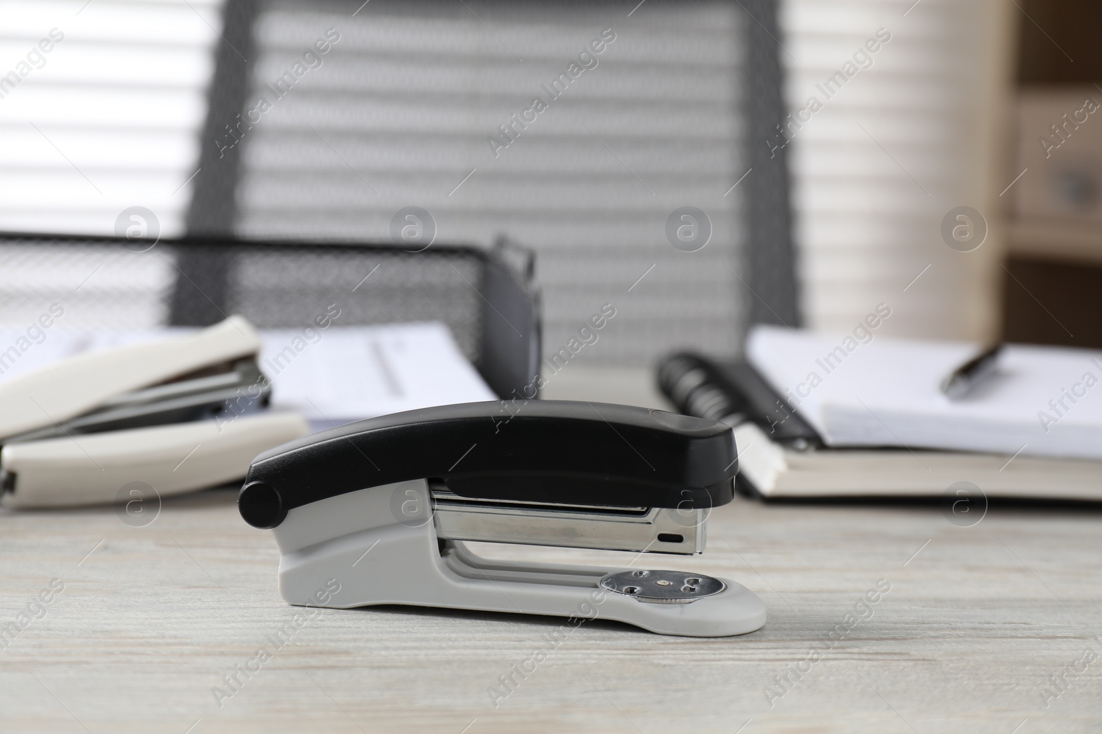 Photo of Stapler on wooden table, closeup. Office stationery