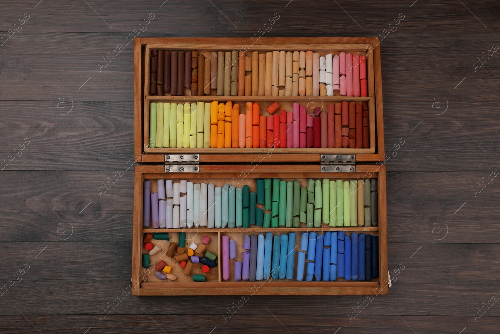 Photo of Drawing pastel set in box on wooden background, top view