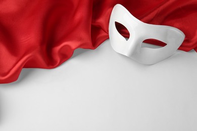 Photo of Theatre mask and red fabric on white background, above view. Space for text