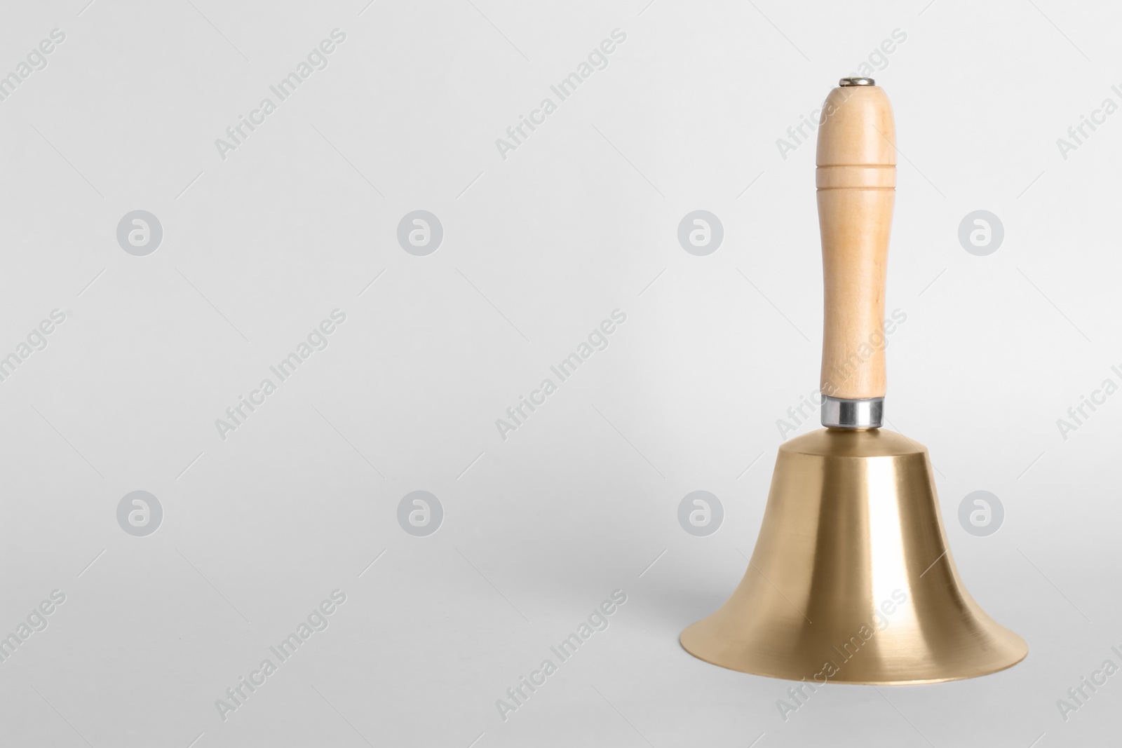 Photo of Golden school bell with wooden handle on grey background. Space for text