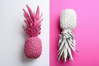 Pink and white pineapples on color background, flat lay. Creative concept