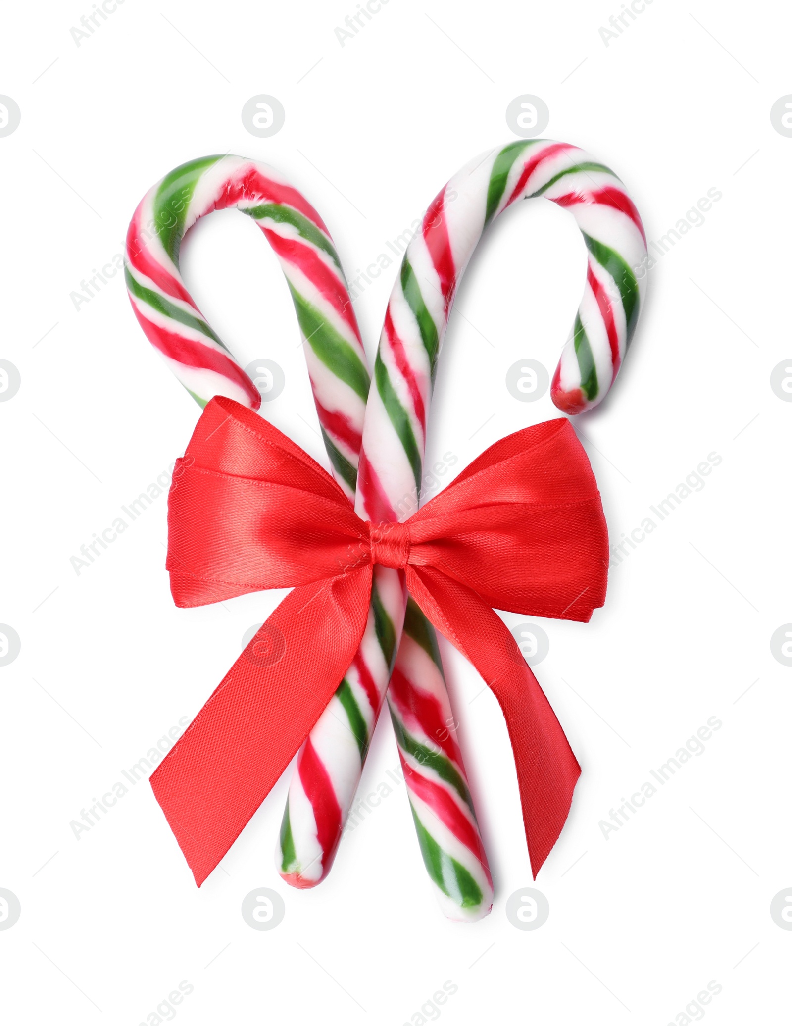 Photo of Sweet Christmas candy canes with red bow on white background, top view