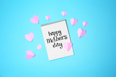 Photo of Notebook with phrase "HAPPY MOTHER'S DAY" and paper hearts on color background