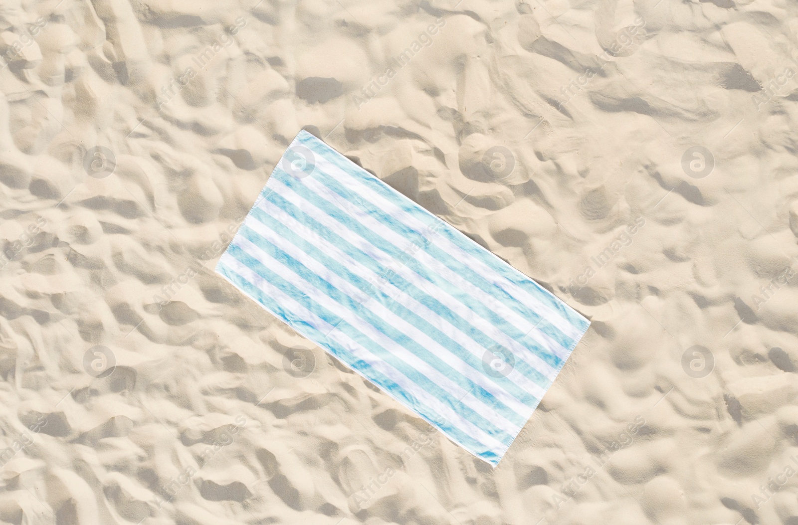 Image of Striped beach towel on sand, aerial view