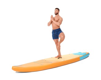 Happy man practicing yoga on orange SUP board against white background