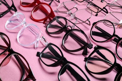 Many different stylish glasses on pink background, closeup