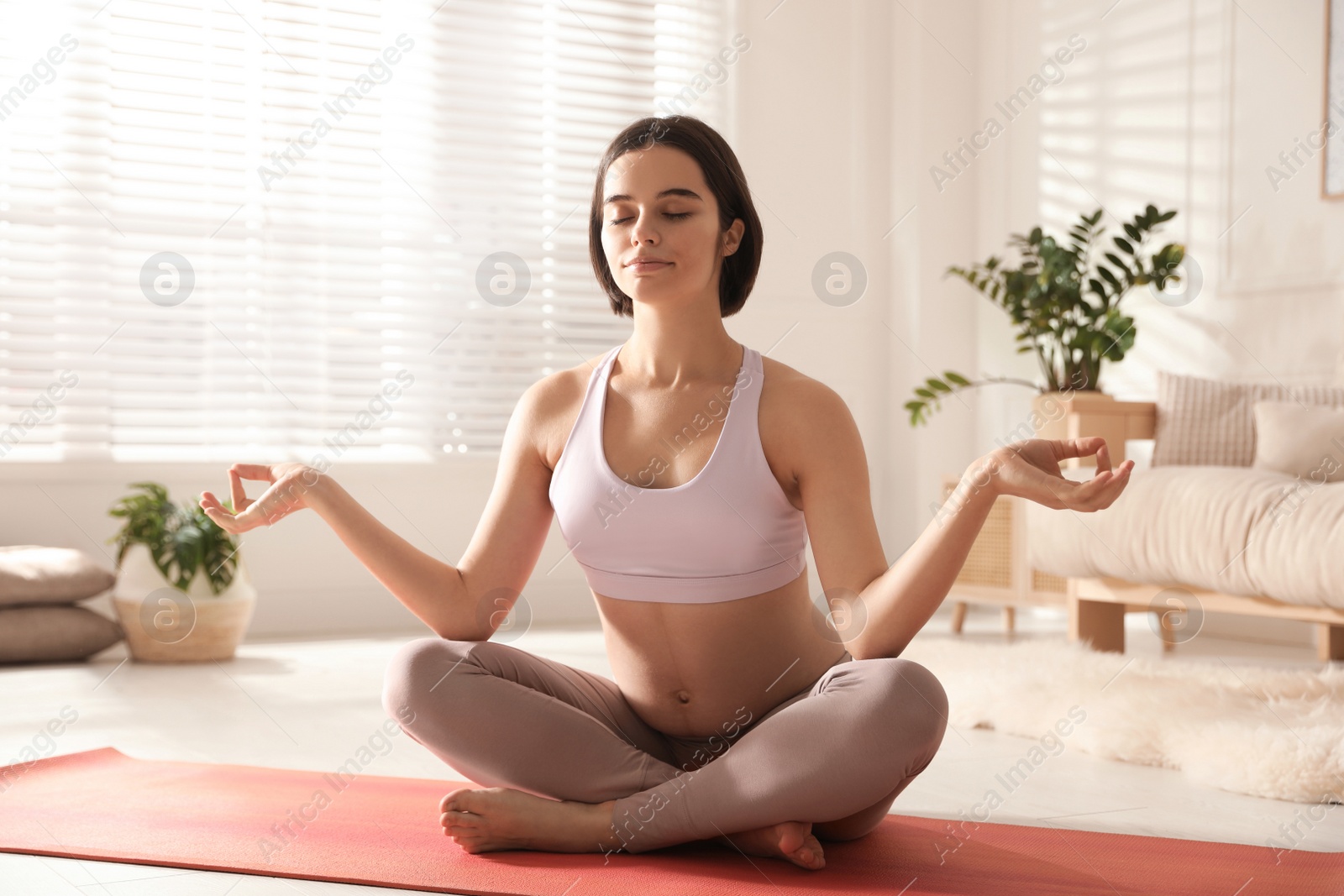 Photo of Young pregnant woman practicing yoga at home