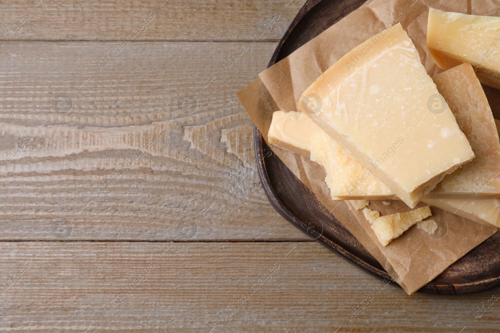 Photo of Pieces of delicious parmesan cheese on wooden table, top view. Space for text