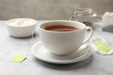 Photo of Brewing tea. Cup with tea bag on light table