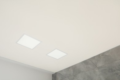 Photo of White ceiling with modern lighting in room, low angle view