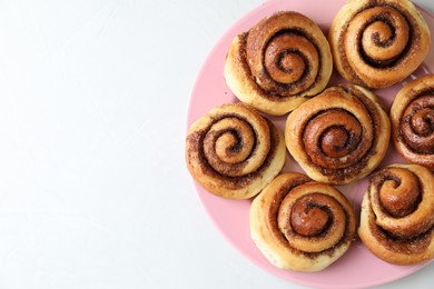 Many tasty cinnamon rolls on white table, top view. Space for text