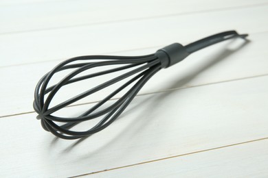 Photo of Plastic whisk on white wooden table, closeup