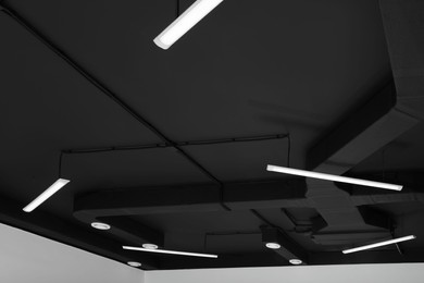 Black ceiling with modern lighting in room, low angle view