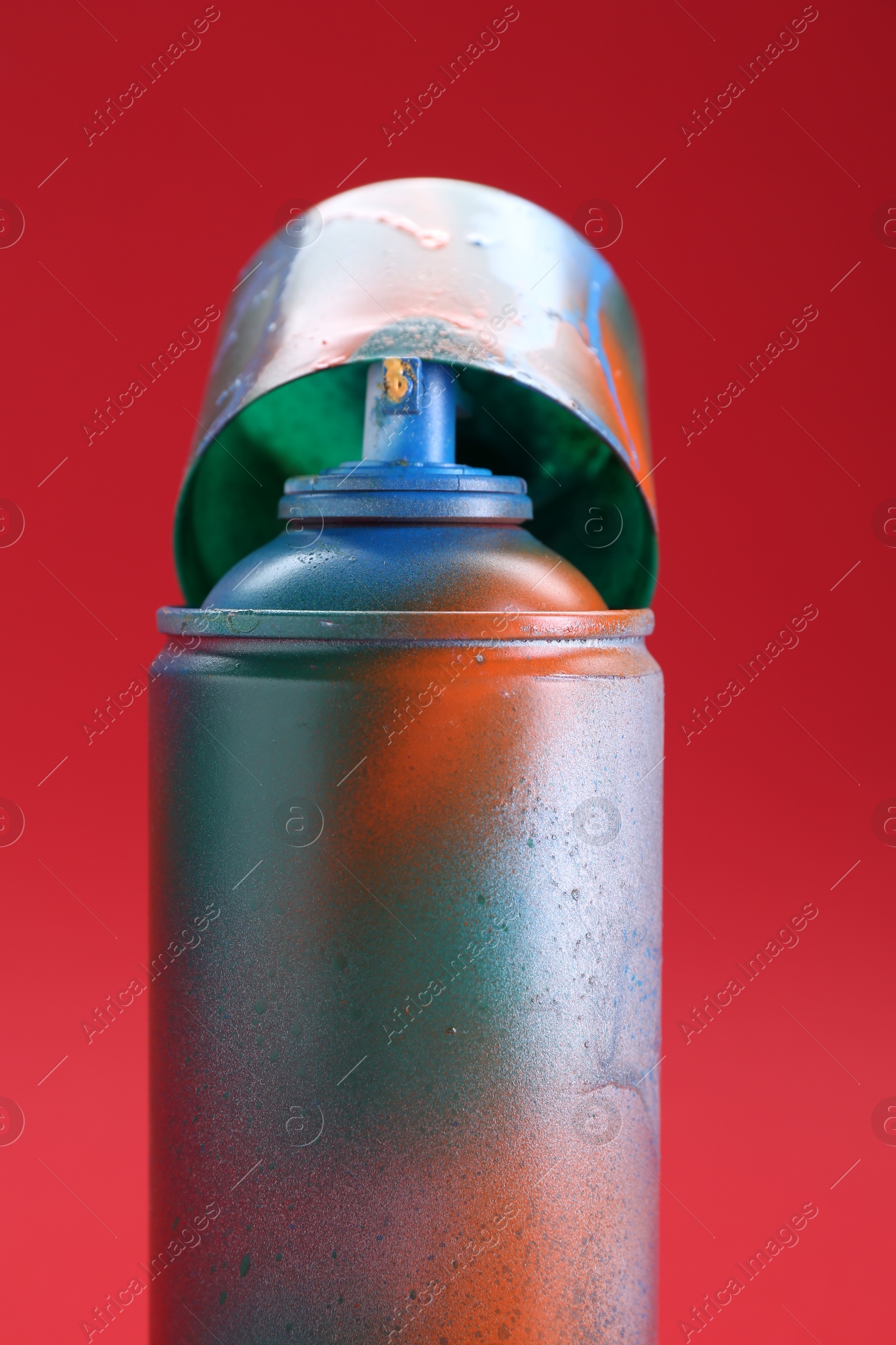 Photo of One can of bright spray paint with cap on red background, closeup