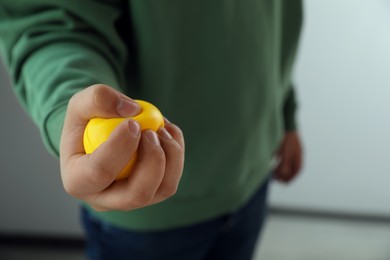 Photo of Man squeezing yellow stress ball indoors, closeup