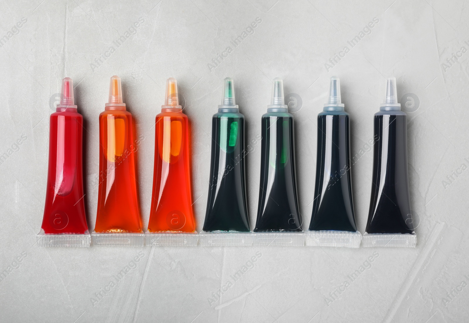 Photo of Tubes with different food coloring on white background, flat lay