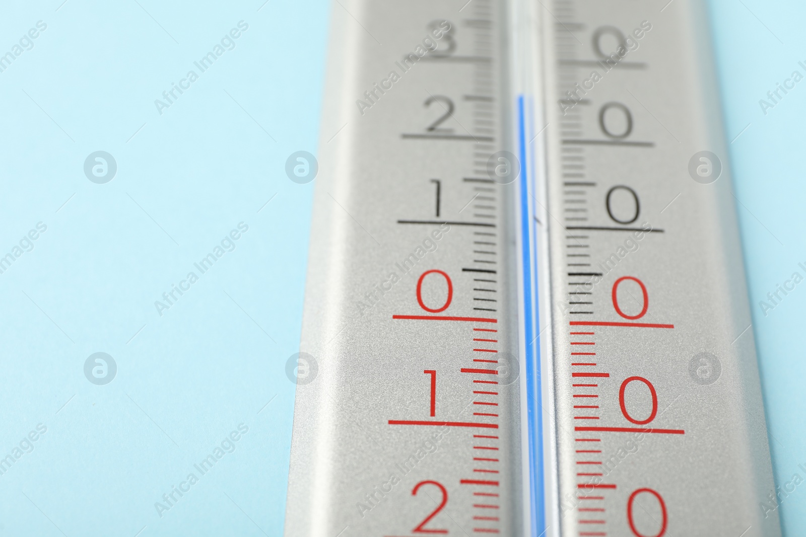 Photo of Weather thermometer on light blue background, closeup. Space for text