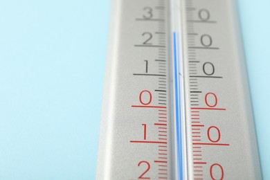 Photo of Weather thermometer on light blue background, closeup. Space for text