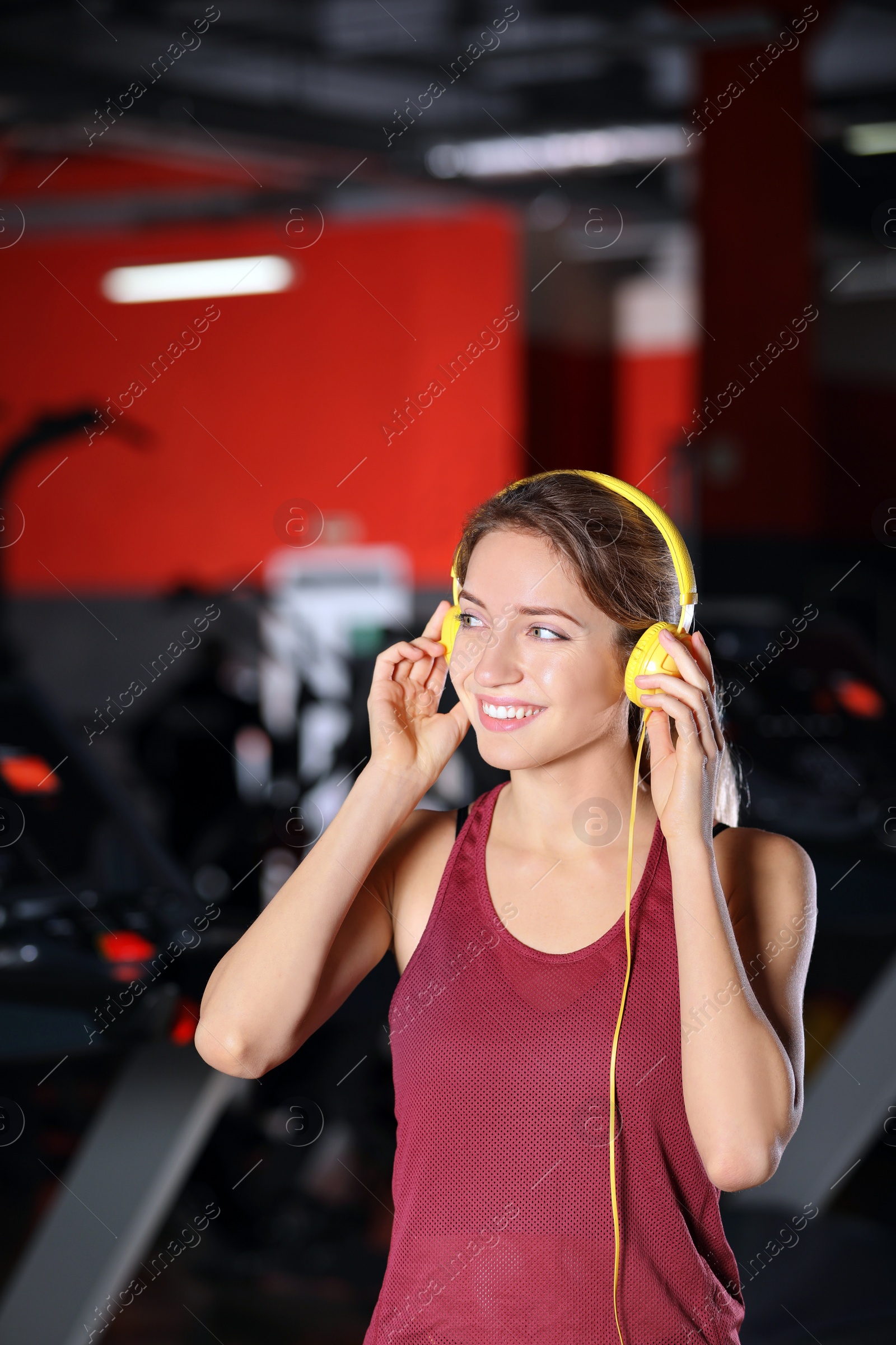 Photo of Young woman listening to music with headphones at gym