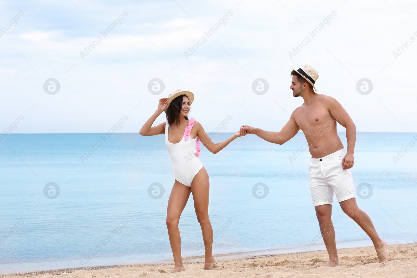 Photo of Happy young couple walking together on beach near sea