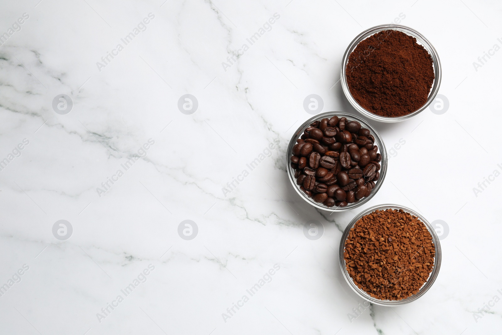 Photo of Bowls of beans, instant and ground coffee on white marble table, flat lay. Space for text