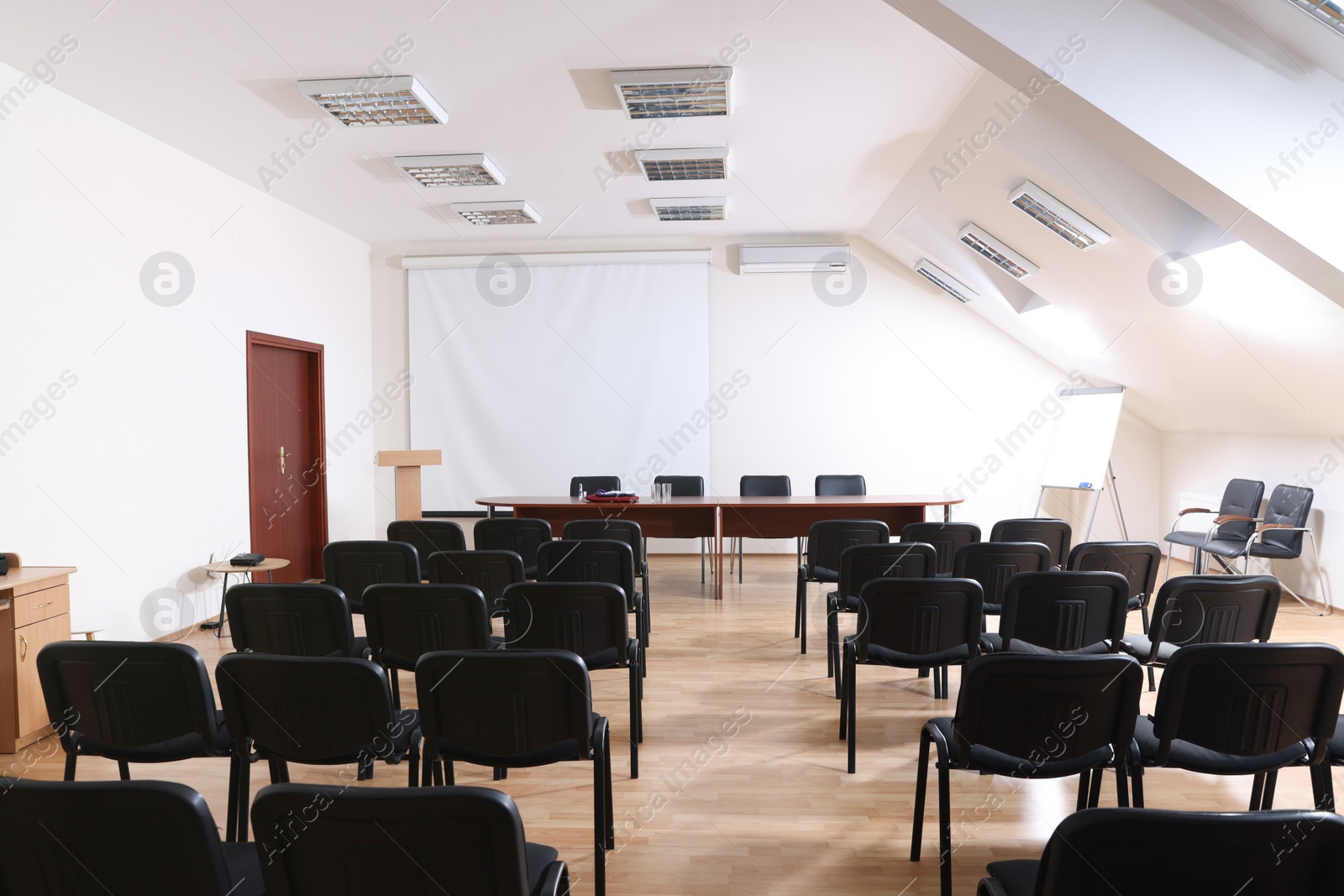 Photo of Empty conference room with projection screen, wooden table and many chairs