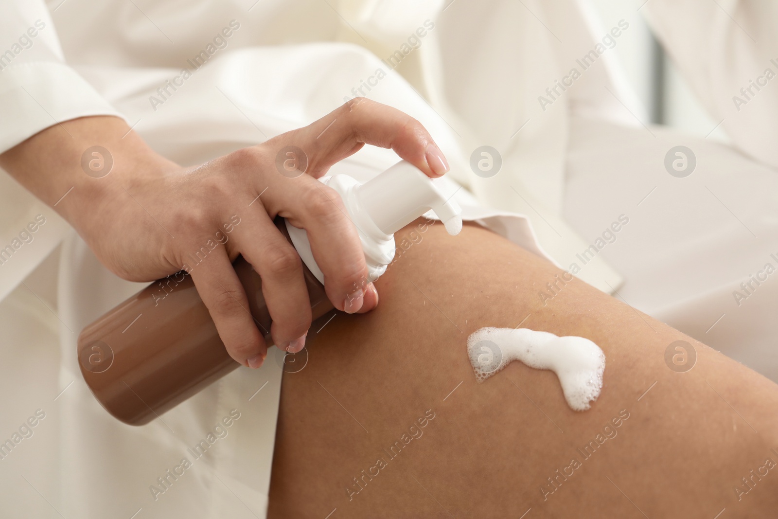 Photo of Woman applying self-tanning product onto leg, closeup