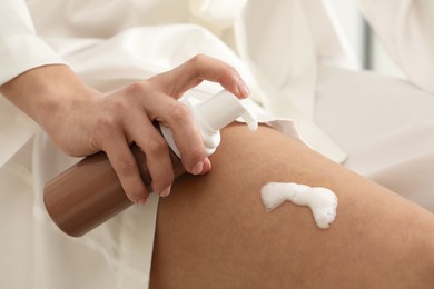 Photo of Woman applying self-tanning product onto leg, closeup