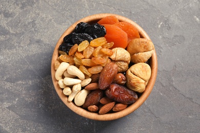 Bowl with different dried fruits and nuts on table, top view