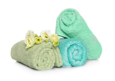 Photo of Rolled soft terry towels and flowers on white background