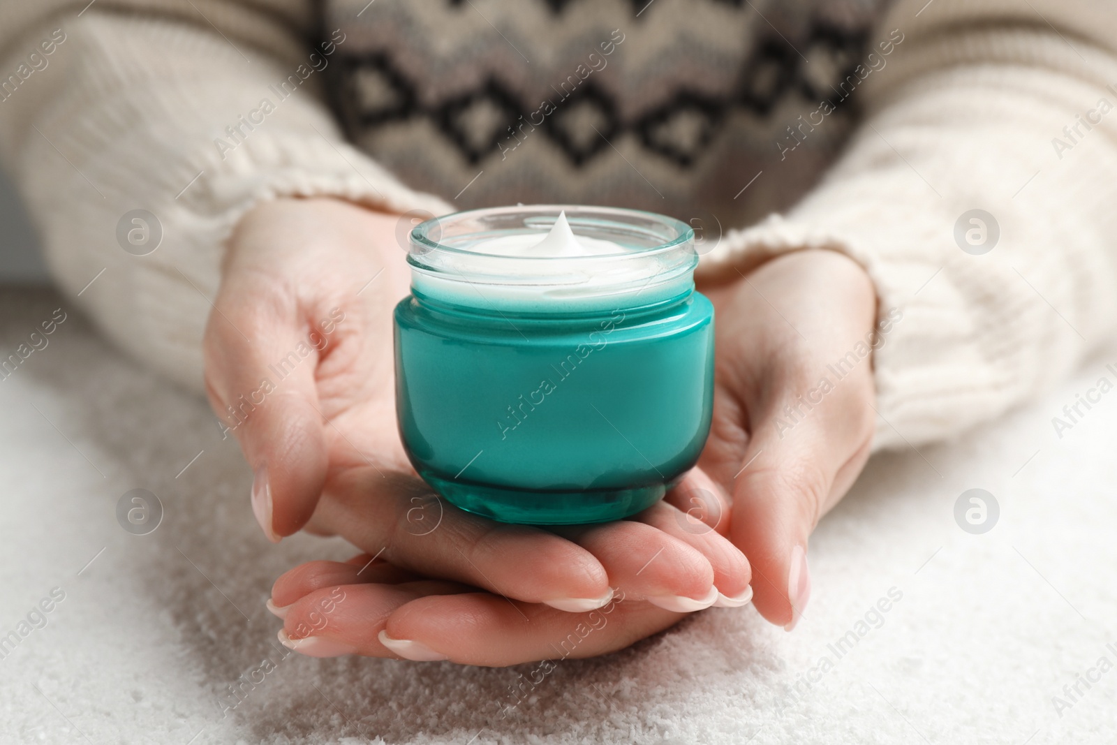 Photo of Woman with jar of hand cream over snow, closeup