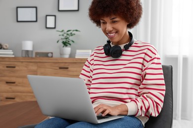 Beautiful young woman using laptop in room