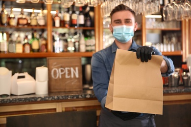 Waiter with packed takeout order in restaurant. Food service during coronavirus quarantine