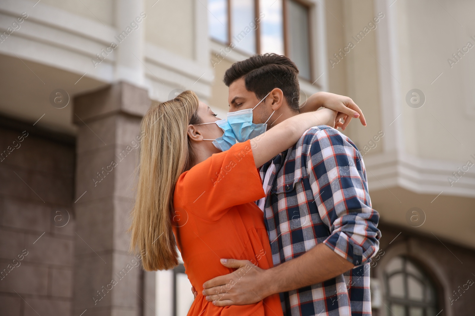 Photo of Couple in medical masks trying to kiss outdoors