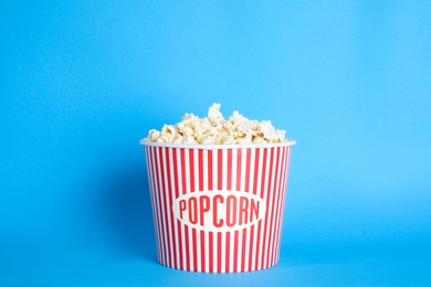 Bucket of fresh tasty popcorn on color background. Cinema snack