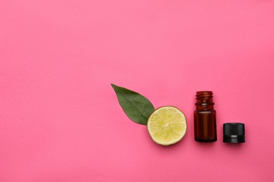 Bottle of citrus essential oil and fresh lime on pink background, flat lay. Space for text