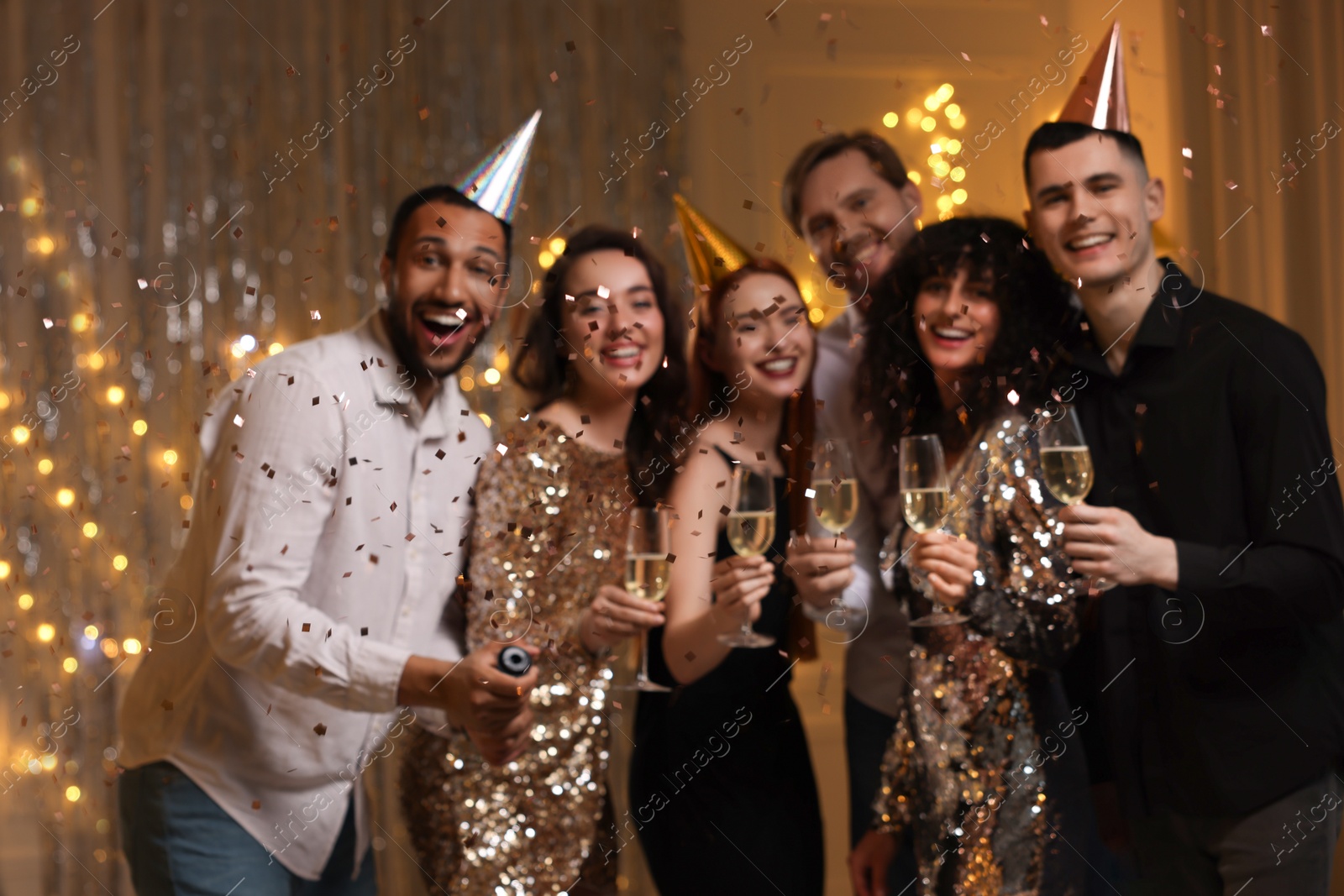 Photo of Blurred view of happy friends with glasses of sparkling wine celebrating birthday indoors