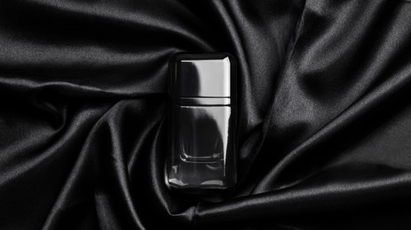 Photo of Luxury bottleperfume on black silk, top view