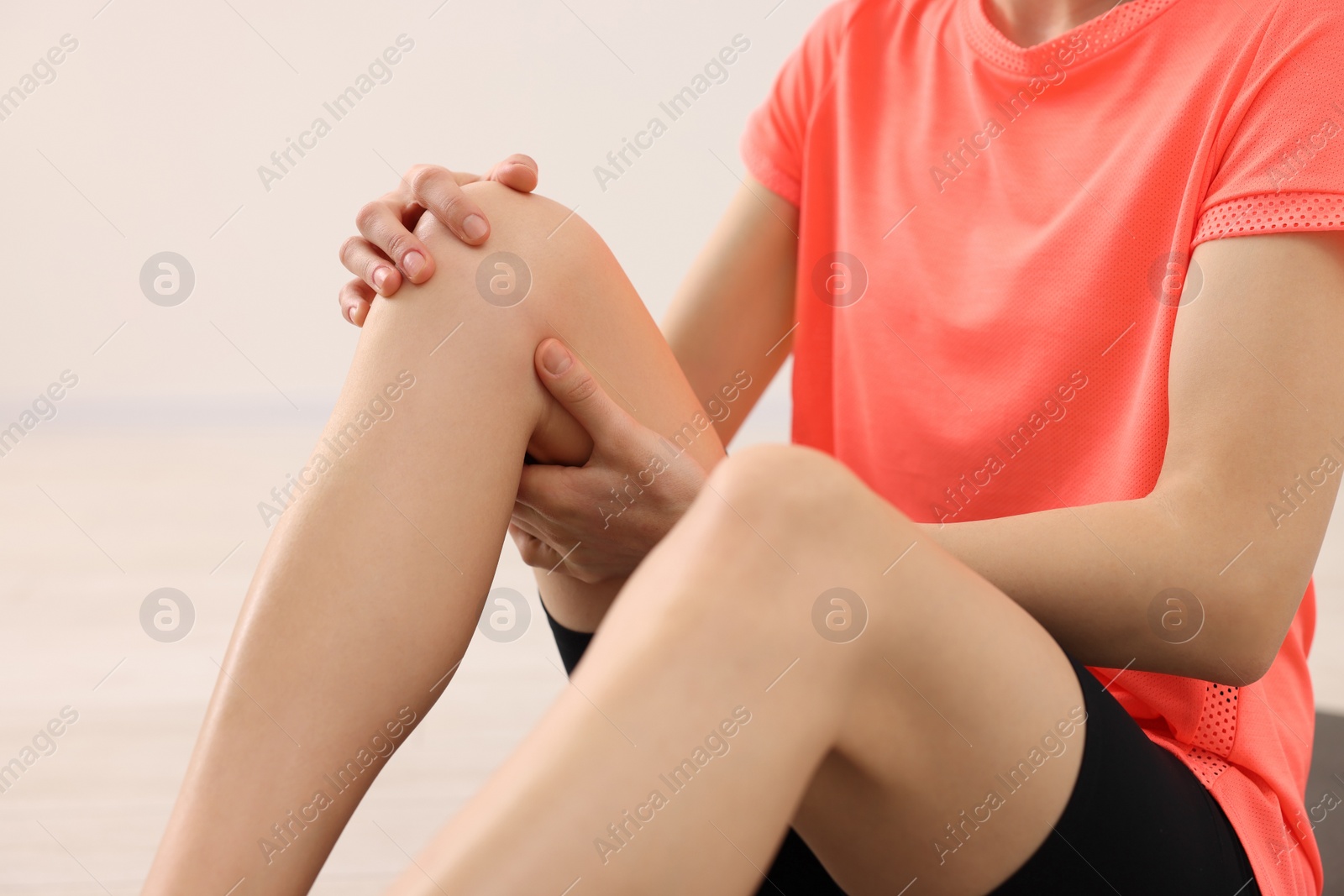 Photo of Woman suffering from leg pain indoors, closeup