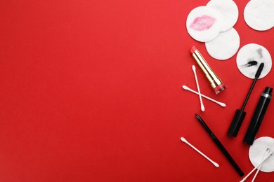 Photo of Dirty cotton pads, swabs and cosmetic products on red background, flat lay. Space for text