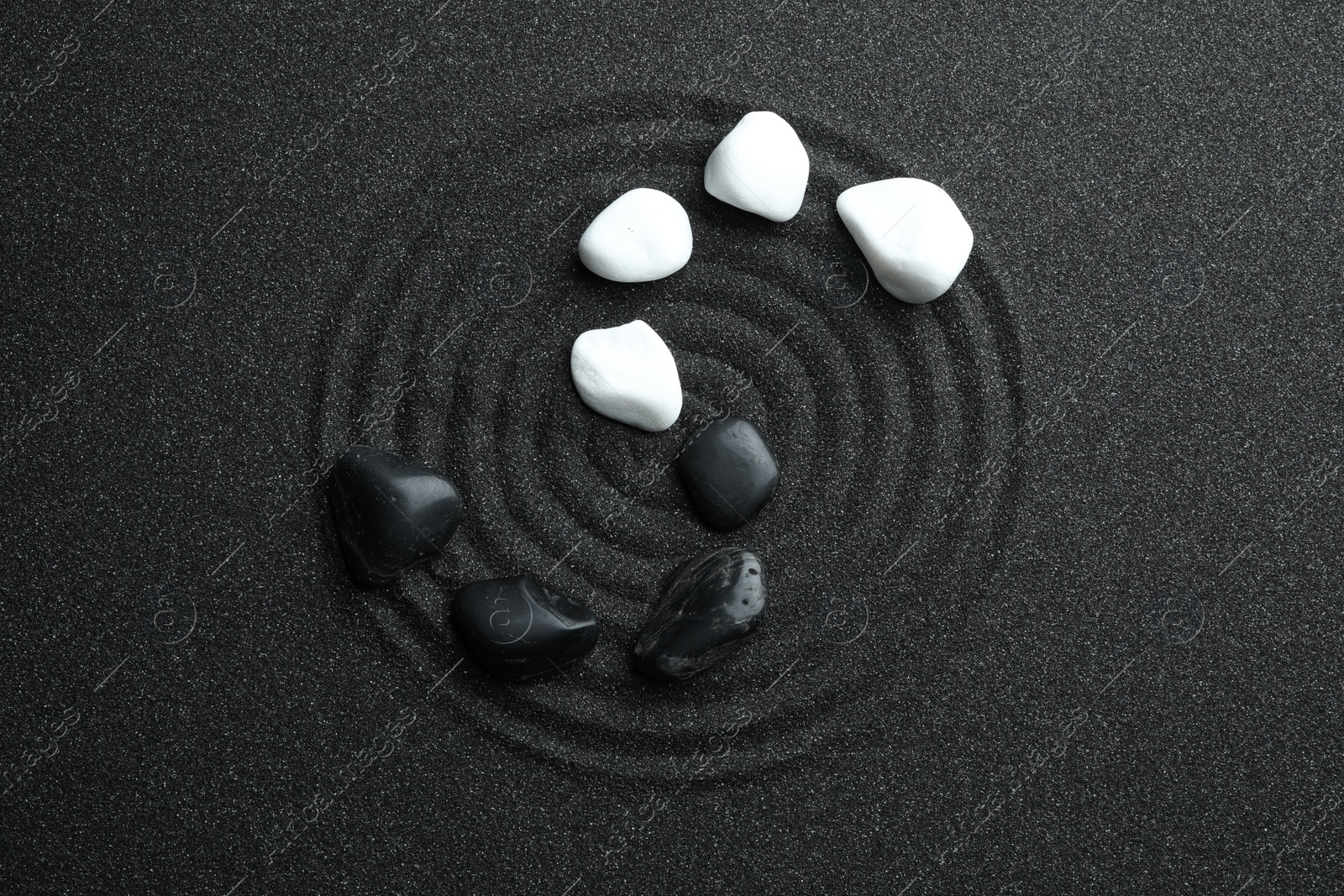 Photo of Stones on black sand with beautiful pattern, flat lay. Zen and harmony