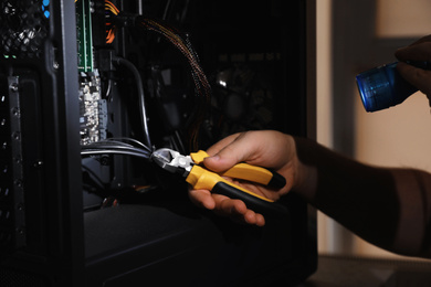 Photo of Man with flashlight fixing system unit indoors, closeup