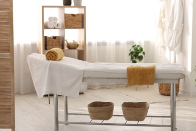 Comfortable massage table with clean towels in spa center