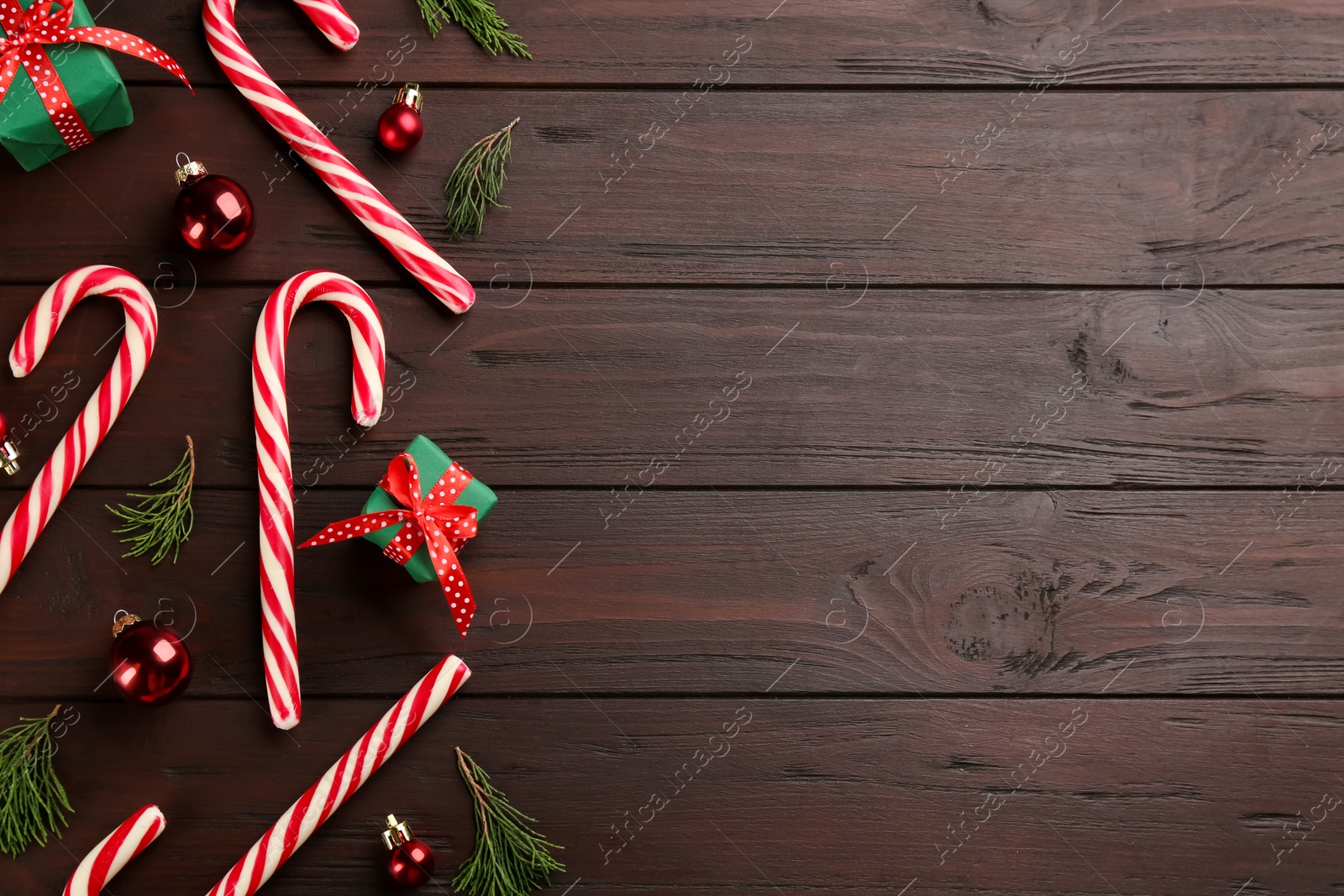 Photo of Flat lay composition with candy canes and Christmas decor on wooden table. Space for text